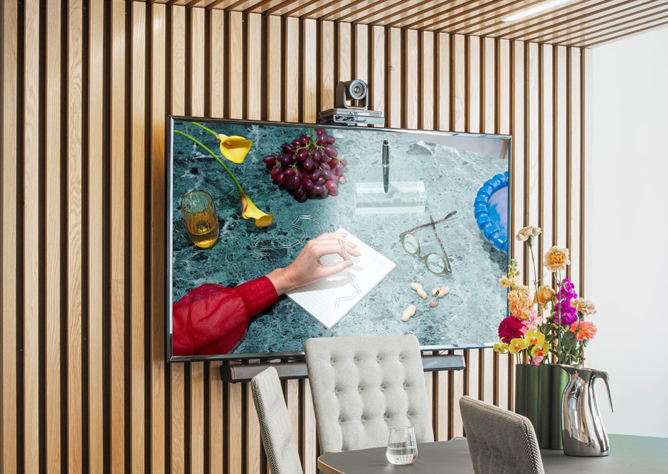 Møterommet Arbin med grå tekstilstoler, mørkegrått bord med fargerik blomsteroppsats